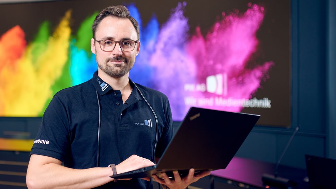 PIK Enterprise-Techniker mit Laptop vor Videowall