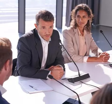 Zwei Personen in Konferenzsituation mit Televic-Mikrofonen im Boardroom-Setting