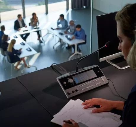 Dolmetscherin an Televic-Dolmetscherkonsole mit Blick auf den Konferenzraum