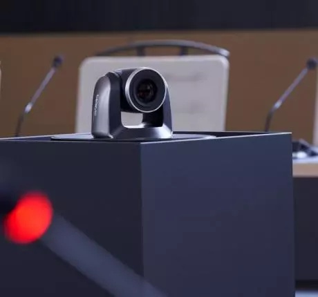 PTZ-Kamera auf Konferenztisch mit Mikrofonen im Hintergrund